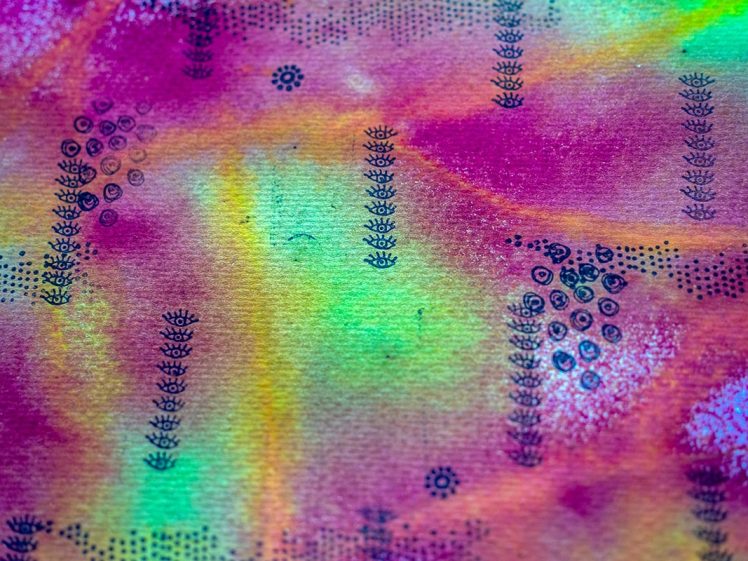 Image of A close-up of colourful abstract art with vibrant hues of pink, green, and yellow, featuring black dotted and small floral patterns scattered across a textured surface.