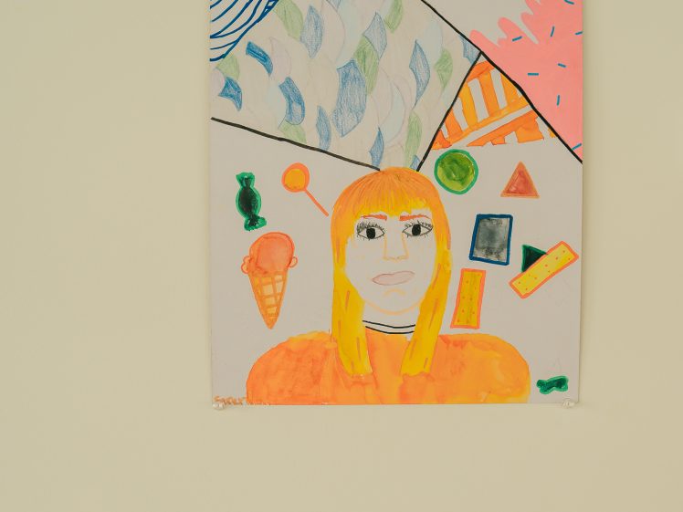 Image of A colourful drawing of a person with orange hair, set against a vibrant geometric background featuring abstract shapes, patterns, and objects like an ice cream cone, leaves, and rectangles. The artwork is displayed on a wall.